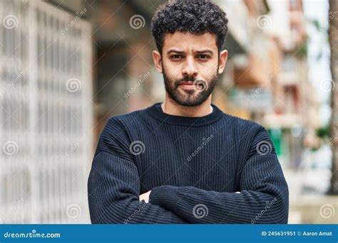 Young Arab Man With Relaxed Expression Standing With Arms Crossed