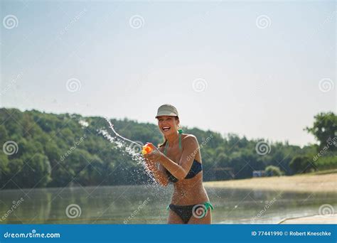 Woman At A Lake Spraying With A Squirt Gun Stock Photo Image Of Spray Bikini