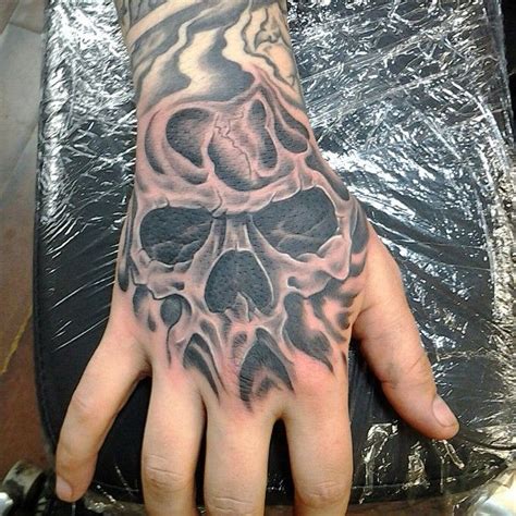 A Mans Hand With A Skull Tattoo On It