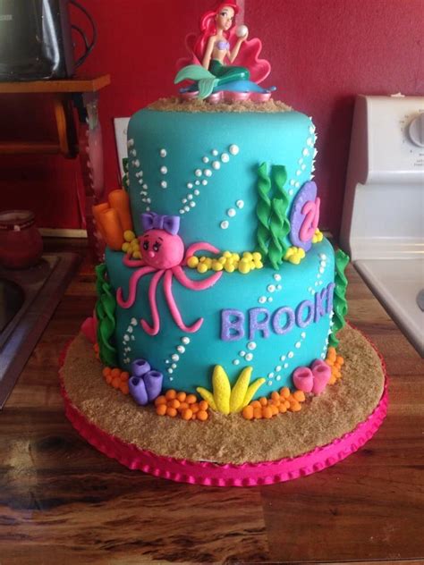 There Is A Cake Decorated With An Image Of A Mermaid On The Top And
