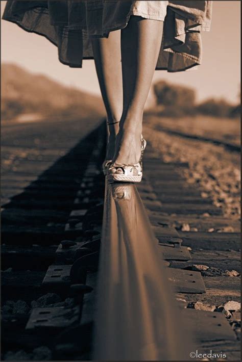 A Womans Legs And Shoes Walking On Train Tracks With Sunlight