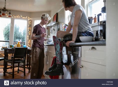Young Woman Amputee Watching Boyfriend Eating In Kitchen Stock Photo