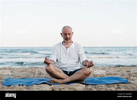 Senior Man Doing Yoga Meditation Outdoor At The Beach Elderly And