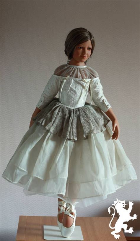 A Doll Is Standing On Top Of A Table With A White Dress And Shoes In