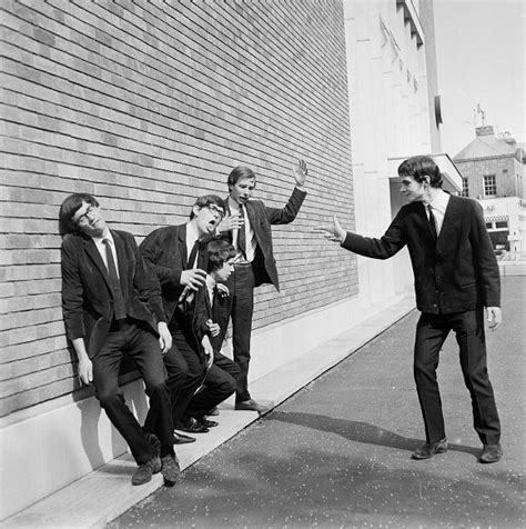the beatles leaning against a brick wall with their hands in each other s pockets