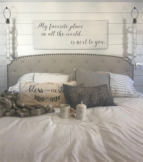 A White Bed Topped With Lots Of Pillows Next To A Wall Mounted Wood