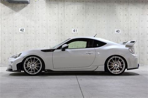 A White Sports Car Is Parked In A Garage With Numbers On The Wall Behind It