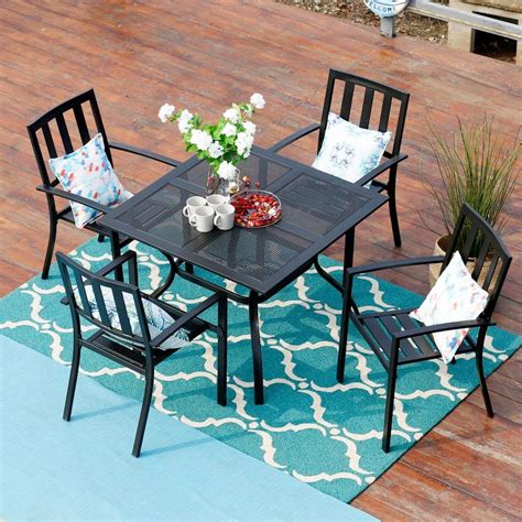 an outdoor dining table and chairs on a patio with blue rug potted plant and white flowers