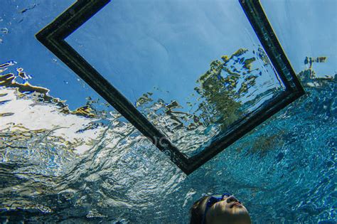 Teenage Girl Underwater Looking Through Frame On Water Surface — Only