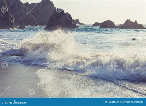 Beautiful Rocky Beach And Ocean Wave Under Blue Cloudy Summer Sky Stock