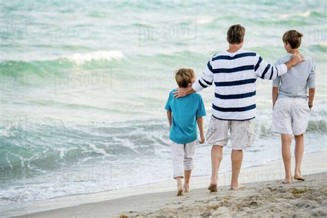 Caucasian Father And Sons Walking On Beach Stock Photo Dissolve