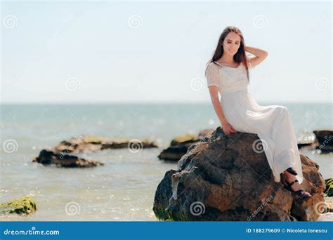 Woman With Long Dress Sitting On Rocks By The Sea Stock Image Image