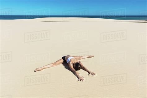 Woman On Beach In Yoga Position Bending Forward Doing The Splits