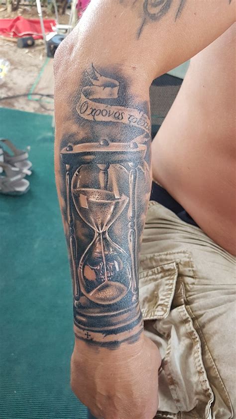 A Man With A Tattoo On His Arm Has An Hourglass In Front Of Him