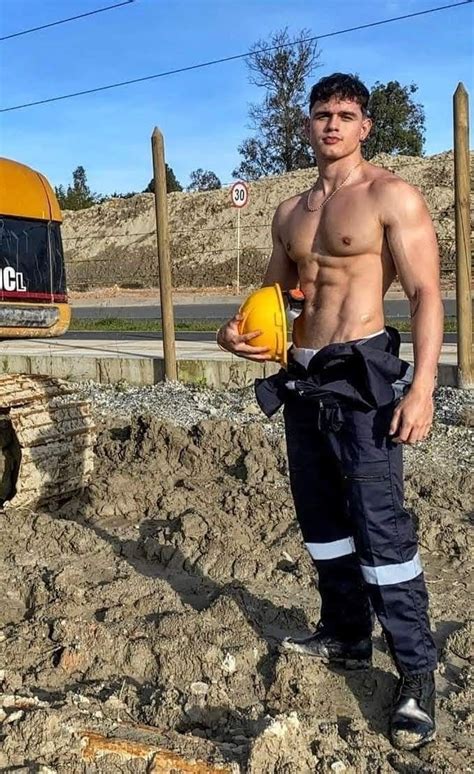 A Shirtless Man Standing In Front Of A Bulldozer Holding A Yellow Ball