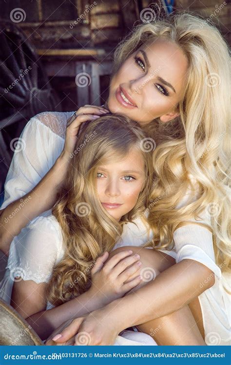 Beautiful Young Mother With Her Daughter Dressed In Spring Clothes And Wreaths Of Flowers Stock