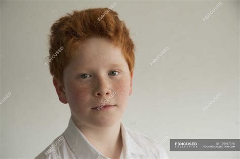 Portrait Of Boy With Red Hair And Freckles Against Grey Background