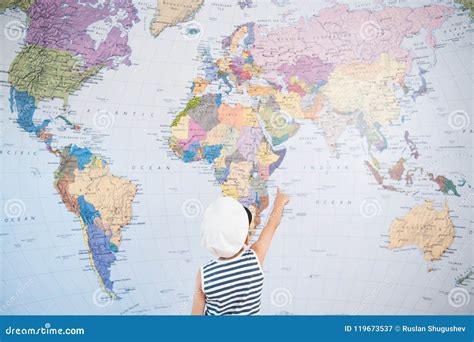 Little Kid In Captain Cap Pointing At World Map With Finger Direction