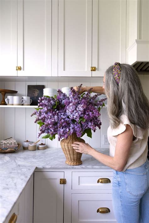 A Woman Arranging Flowers In A Basket On The Kitchen Countertop With