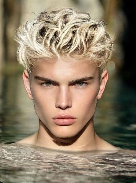 A Man With Blonde Hair Standing In Water Looking At The Camera And