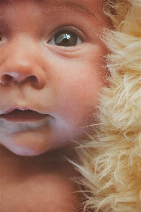 Newborn Baby Stares While Lying On Sheepskin Rug By Stocksy