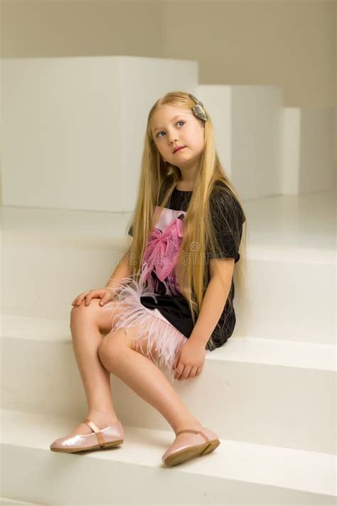 Cute Little Girl Is Sitting In The Studio On The White Stairs Style