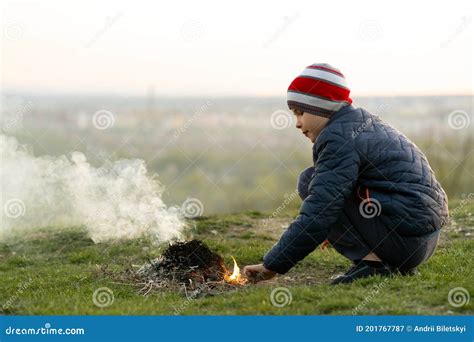 Child Boy Warming Near Bonfire Outdoors In Cold Weather Stock Image