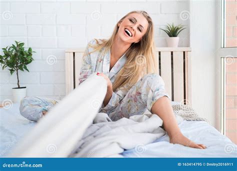 Beautiful Blonde Woman Laughs And Pulls The Blanket Over Herself Playing In Bed Stock Image