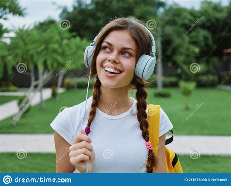 Happy Teenage Girl Listening To Music With Headphones With A Backpack