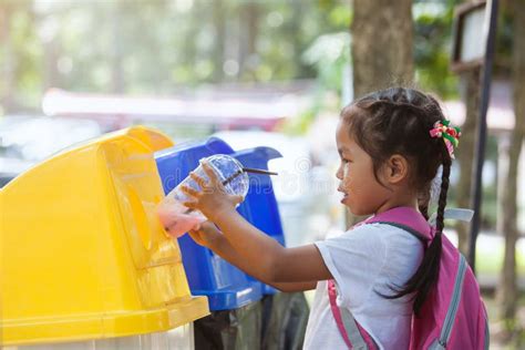 Cute Asian Child Girl Throwing Plastic Glass In Recycling Trash Stock