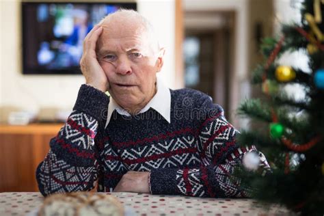 Bored Elderly Man Sitting Alone At Home Table At Christmas Stock Photo