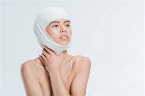 mujer desnuda con vendajes en la cabeza después de una cirugía plástica aislada en blanco