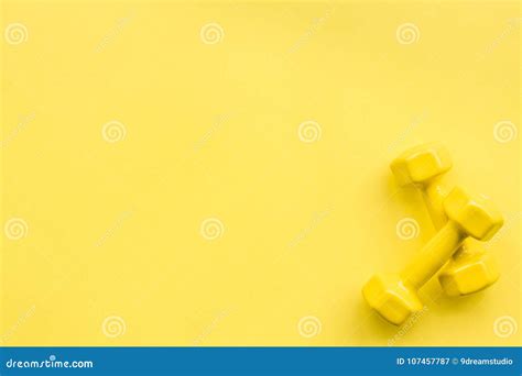 equipment for sport exercise fitness background dumbbells expander on pastel yellow