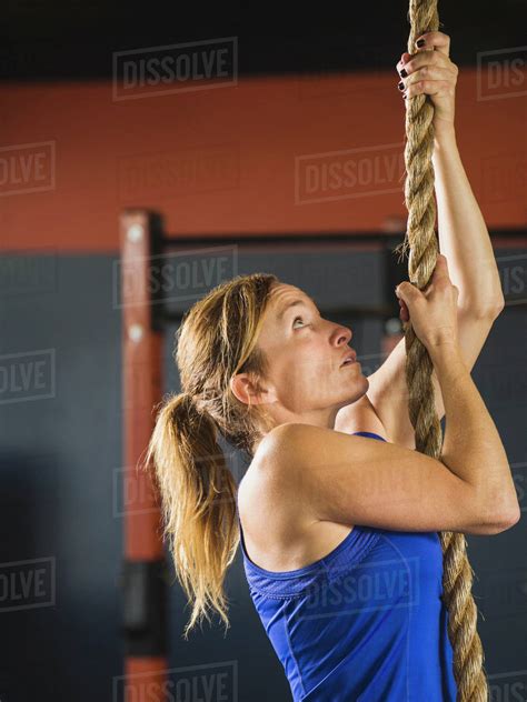 Caucasian Woman Climbing Rope In Gym Stock Photo Dissolve