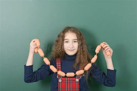 Schoolgirl Near Green School Board Young Playful Girl Hold The Chain Of Sausages On Green