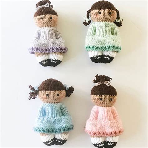 four knitted dolls sitting next to each other on a white surface with one doll in the middle