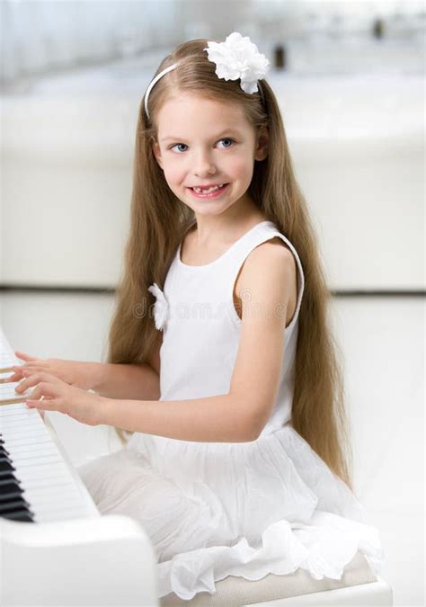 Portrait Of Little Pianist In White Dress Playing Piano Stock Photo