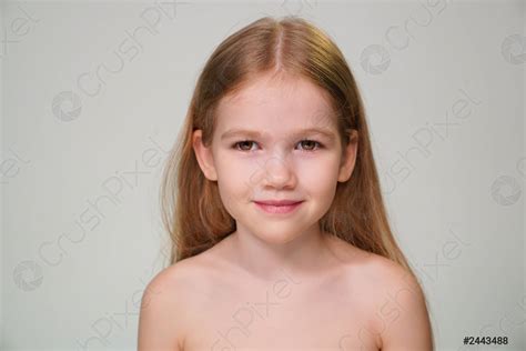A Little Girl With Blond Hair Against A White Wall Stock Photo