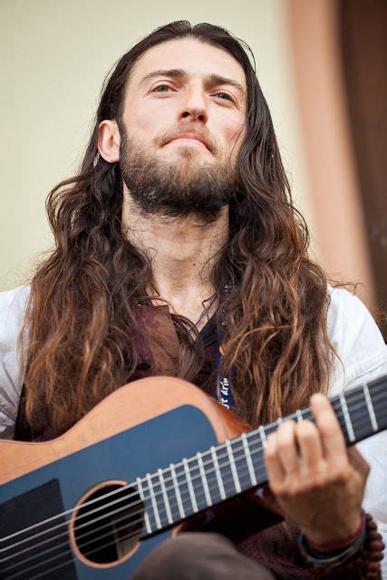 A Man With Long Hair Playing An Acoustic Guitar