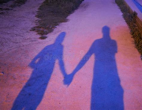 Shadow Of A Couple Holding Hands Projected On The Ground At Night