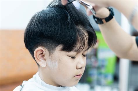 Asian boy is cut his hair in barber shop - people in hairdresser beauty