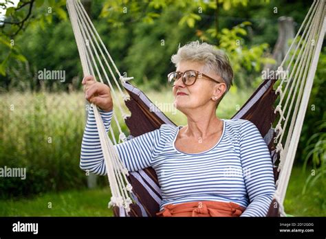 Portrait Of Happy Senior Woman Sitting Outdoors On Hanging Swing Chair