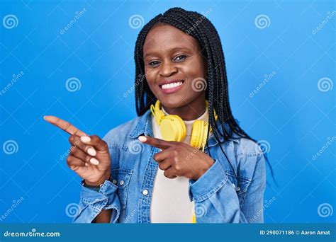 african woman with braids standing over blue background smiling and looking at the camera