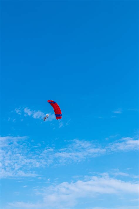 Person In Red Parachute Under Blue Sky During Daytime Photo Free