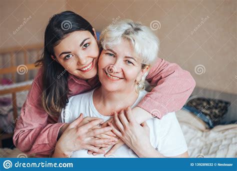 Beautiful Mature Blonde Mom And Her Adult Brunet Daughter Are Hugging