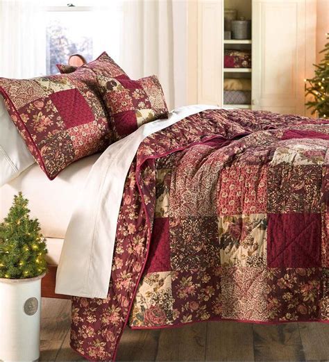A Bed Covered In Red And Gold Quilts Next To A Christmas Tree