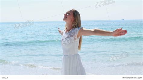 Happy Blonde Woman With Arms Outstretched At The Beach Lizenzfreie