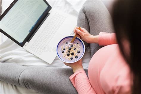 Close Up Of Pregnant Woman Eating Muesli With Blueberries While Working