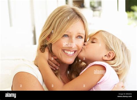 Daughter Giving Mother Kiss Relaxing On Sofa Stock Photo Alamy