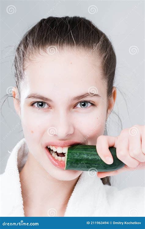 Portrait Of A Beautiful Woman Holding A Cucumber And Biting It On A